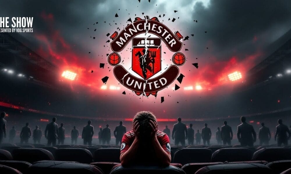 A person sits with their head in hands in a stadium, facing the Manchester United logo, perhaps pondering the decisions made during Ed Woodward's tenure.