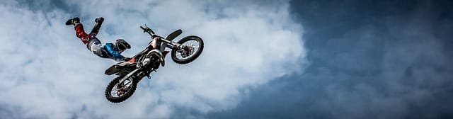 An alternative sports athlete performing a mid-air stunt against a cloudy sky.