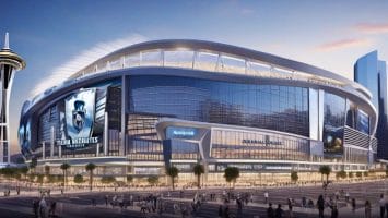 Modern stadium with large screens and distinctive tower nearby, bathed in the warm hues of sunset, surrounded by a bustling cityscape. The air is abuzz with excitement as fans discuss the potential NHL team relocation bringing fresh energy to the town.