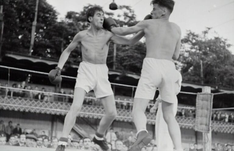 Two boxers face off in the ring, with one landing a punch on the other's face as spectators cheer from the background. The atmosphere buzzes with hot sports takes, fueling the electrifying energy of the match.