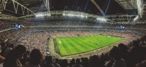 The large stadium buzzes with spectators, enthralled by the soccer match on a well-lit field, as coaches utilize advanced metrics in player evaluation to enhance their strategies.