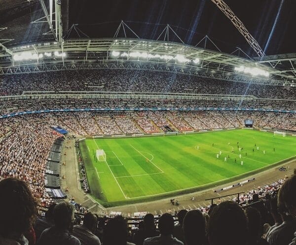 The large stadium buzzes with spectators, enthralled by the soccer match on a well-lit field, as coaches utilize advanced metrics in player evaluation to enhance their strategies.