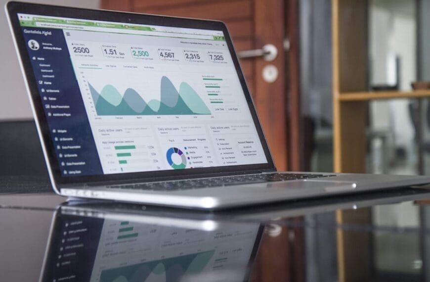A laptop displaying a data analytics dashboard with various graphs and charts sits on a reflective desk surface, offering insights akin to the evolving statistics in modern sports.