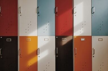 The colorful lockers, arranged in a 3x4 grid and bathed in sunlight, tell silent sports narratives through their varying shades.