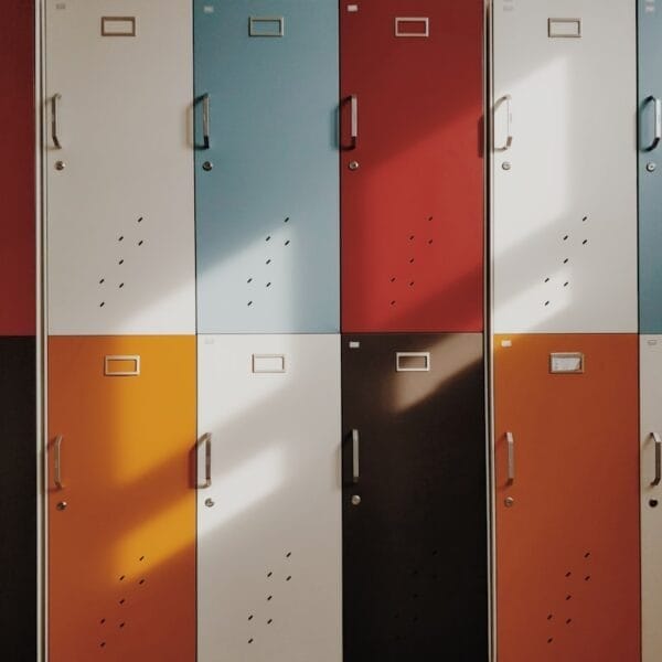 The colorful lockers, arranged in a 3x4 grid and bathed in sunlight, tell silent sports narratives through their varying shades.