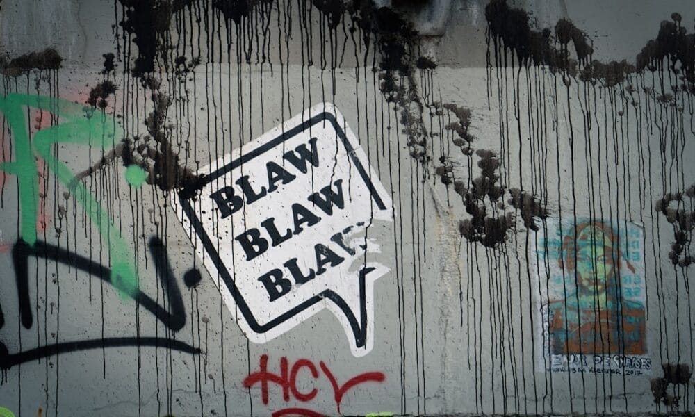 Graffiti on a wall with a speech bubble saying "BLAW BLAW BLAW," where black drips and colorful tags dance around unpopular sports opinions.