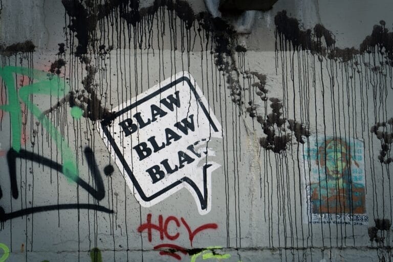 Graffiti on a wall with a speech bubble saying "BLAW BLAW BLAW," where black drips and colorful tags dance around unpopular sports opinions.