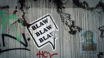 Graffiti on a wall with a speech bubble saying "BLAW BLAW BLAW," where black drips and colorful tags dance around unpopular sports opinions.