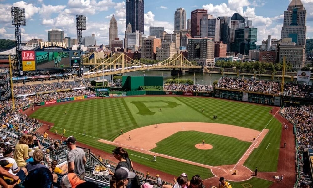 Aerial view of PNC Park during a baseball game, with the Pittsburgh skyline and bridge in the background, captures the essence of America's pastime alongside the evolution of baseball statistics.