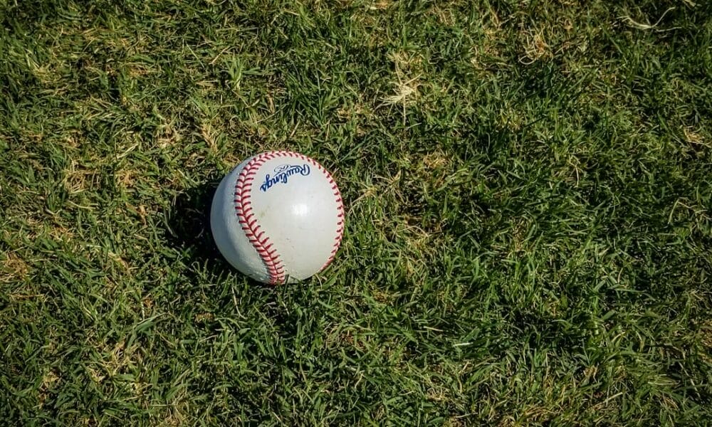 A baseball rests on a grassy field, casting a small shadow, reminiscent of the nuanced precision found in advanced baseball stats.