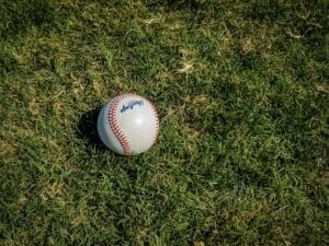 A baseball rests on a grassy field, casting a small shadow, reminiscent of the nuanced precision found in advanced baseball stats.