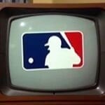 A vintage TV displays the MLB logo—its iconic white silhouette of a batter set against a split blue and red background. The screen is slightly curved, framed in wood, with curtains behind it—a nostalgic nod to days before Breaking MLB Traditions became common.