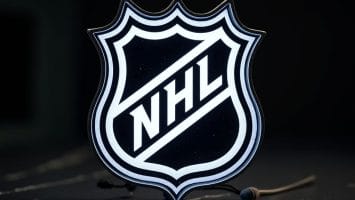 The image shows the official NHL logo, a black and white shield with "NHL" in bold, diagonal letters. The glowing effect on the dark background symbolizes the Evolution of Hockey through time.