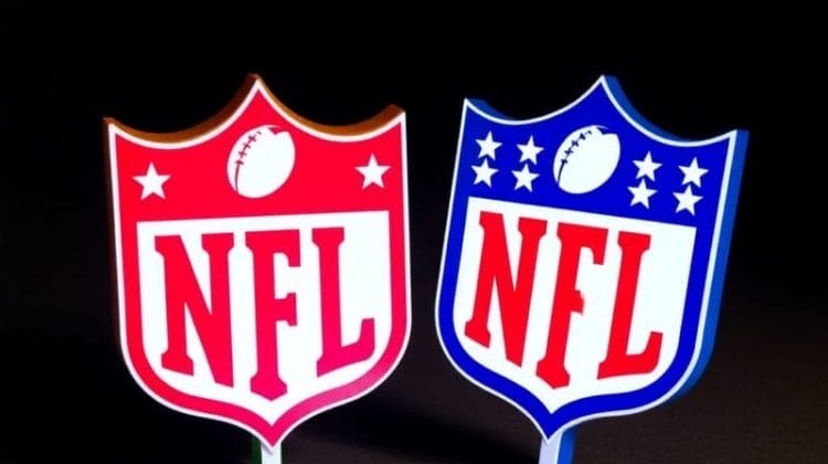 Two illuminated NFL logos on a dark background symbolize great NFL team spirit. The left logo is red with white text and a football icon, while the right logo is blue with white text, stars, and a football icon. Both logos stand upright on their bases, showcasing their vibrant presence.