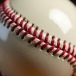 A close-up view of a baseball from the live ball era shows detailed red stitching on white leather. The texture of the leather and twisted threads highlight the craftsmanship and construction typical of this historic period.